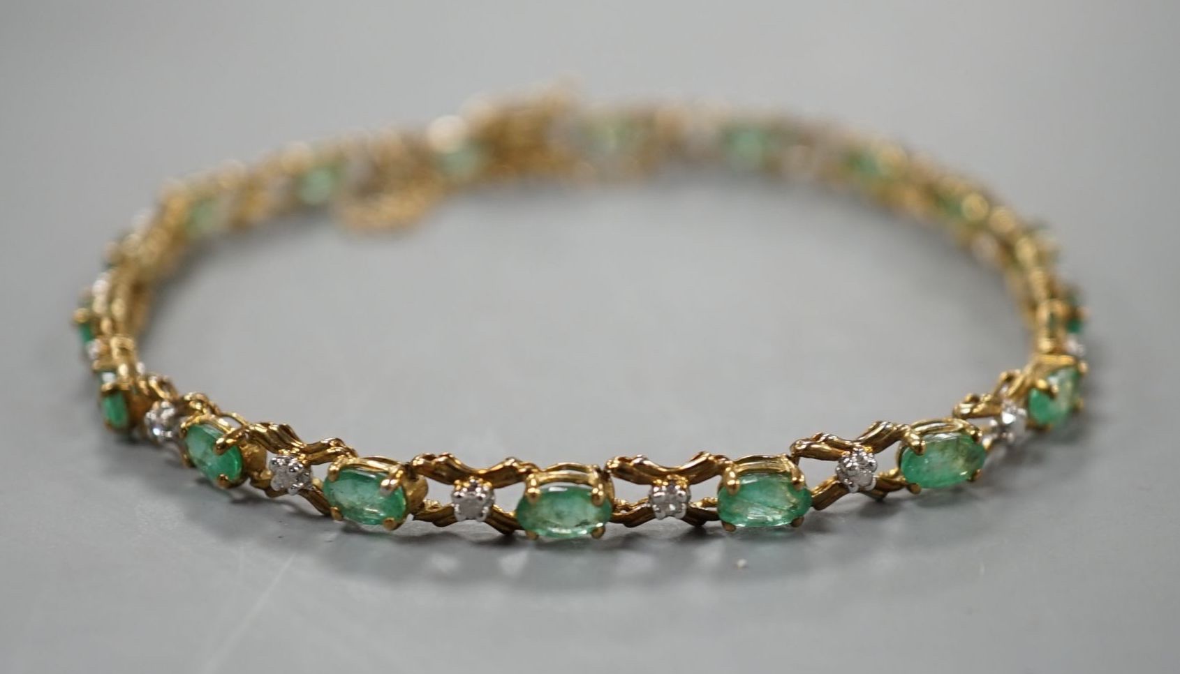 A modern 9ct gold, emerald and diamond chip set line bracelet, approx. 17cm, gross weight 5 grams.